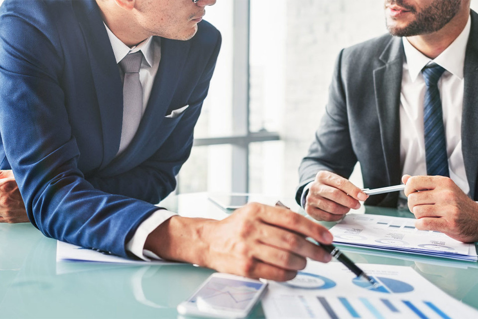 Two men in business suits review graphs and discuss energy as a service model