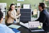 A female presents how green solar energy solutions will benefit a business as a male colleague watches expectantly